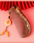 Phoenix wooden comb with carved teeth, gold painted detail, and decorative tassel.
