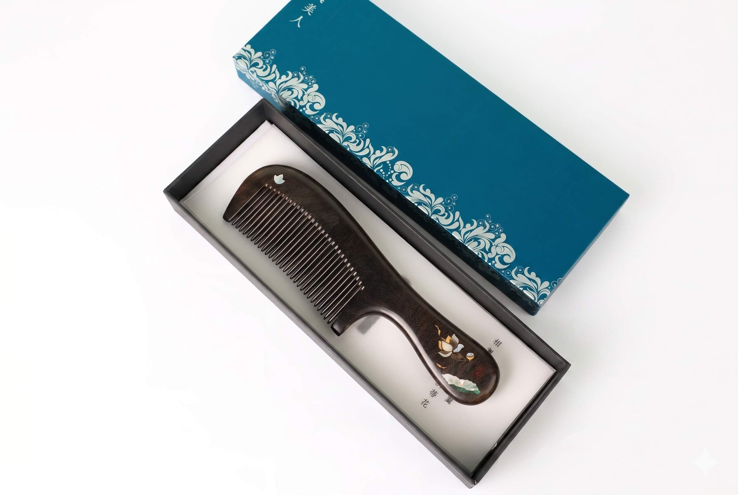 Wooden comb in a decorative box with a blue lid on a white background