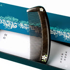 Hair comb with decorative handle on a blue and white floral patterned background