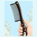 Handheld black ebony wood comb with rounded handle and cat motif
