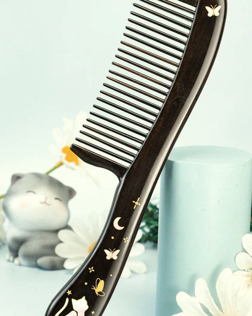 Black ebony cat comb with mother-of-pearl inlay on soft floral background