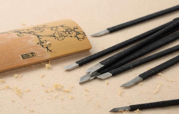 A professional set of traditional bamboo carving knives and chisels used by Master Xu Bingfang, meticulously arranged in a specialized leather tool roll kit
